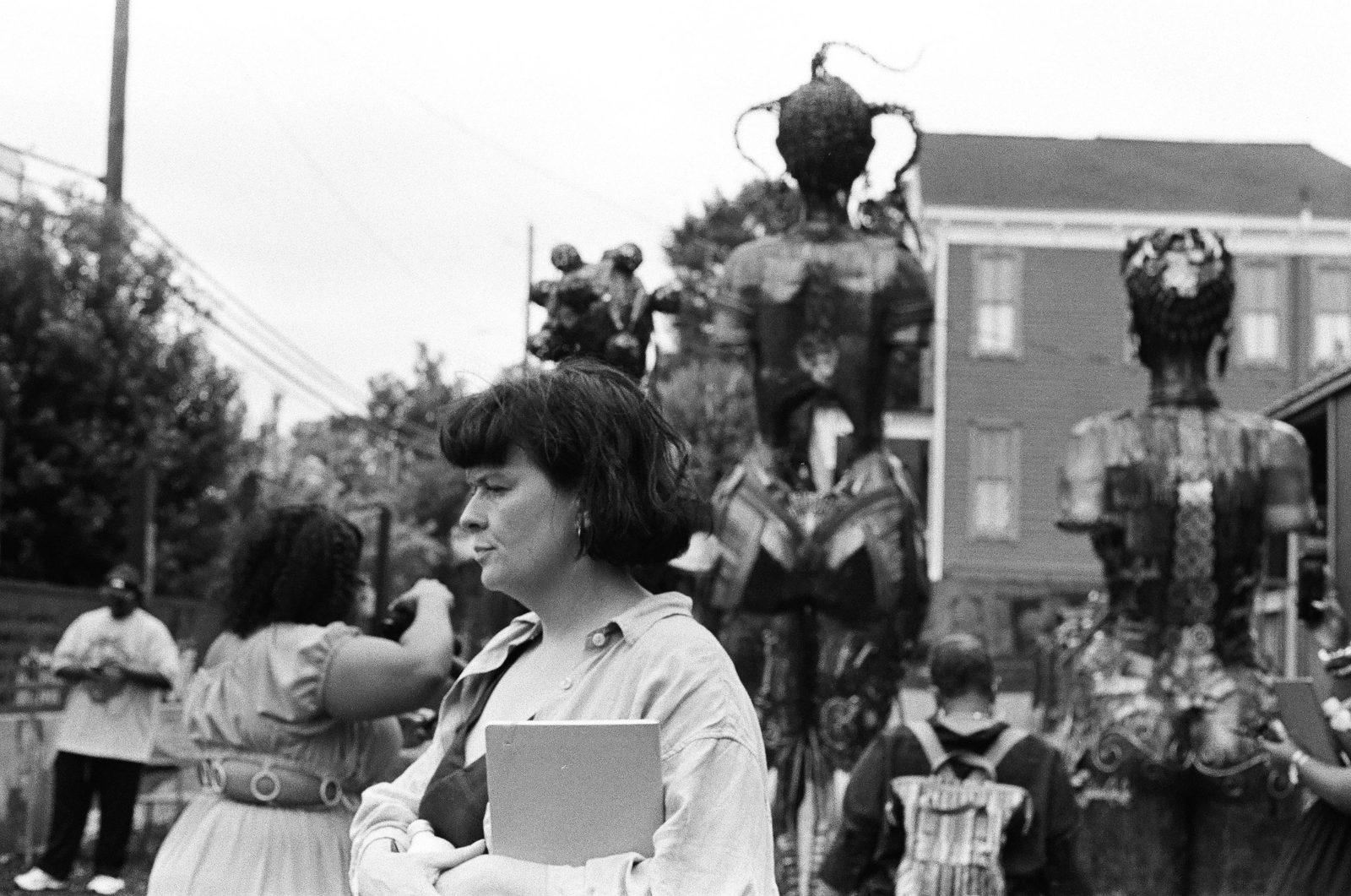 A visitor holding a notebook stands before the Mothers of Gynecology sculptures in Montgomery, seen from behind.
